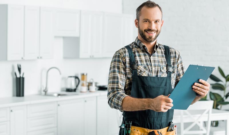 young professional holding a notepad standing inside of a kitchen